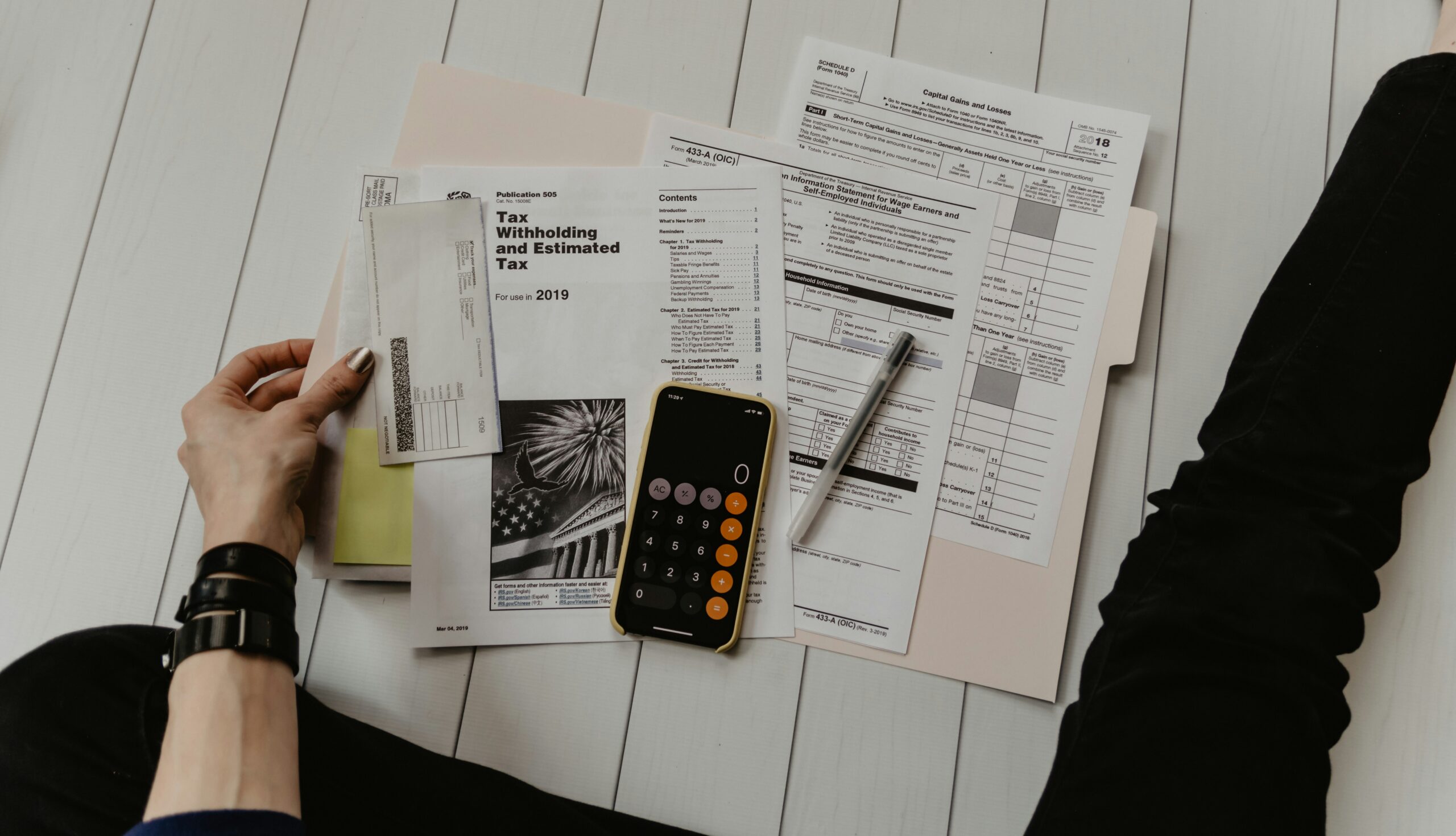 Person holding paper near pen and calculator.